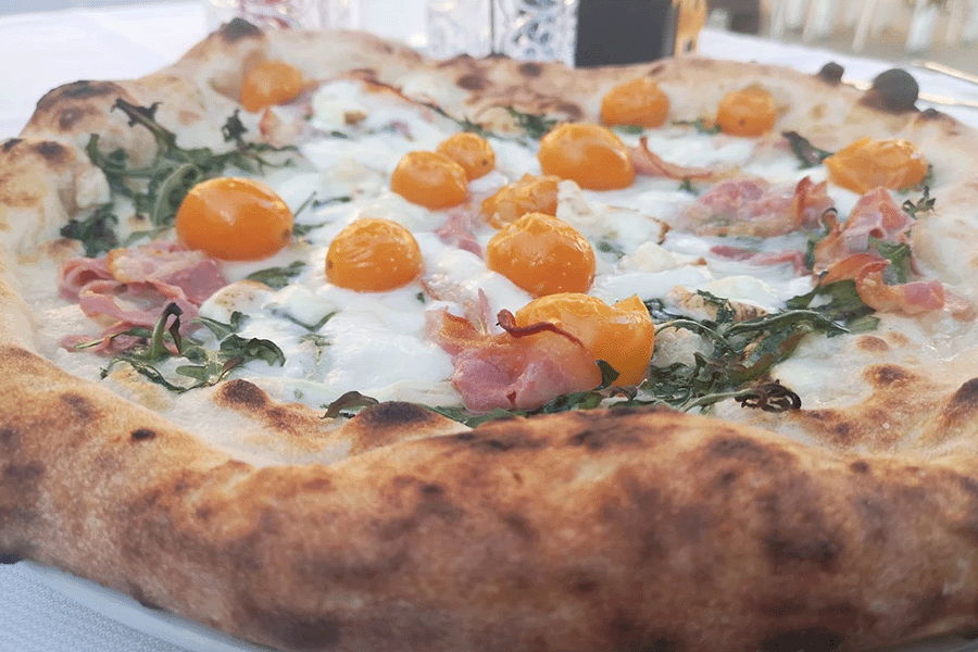 pizza con mozzarella, prosciutto cotto erbe e pomodorini gialli
